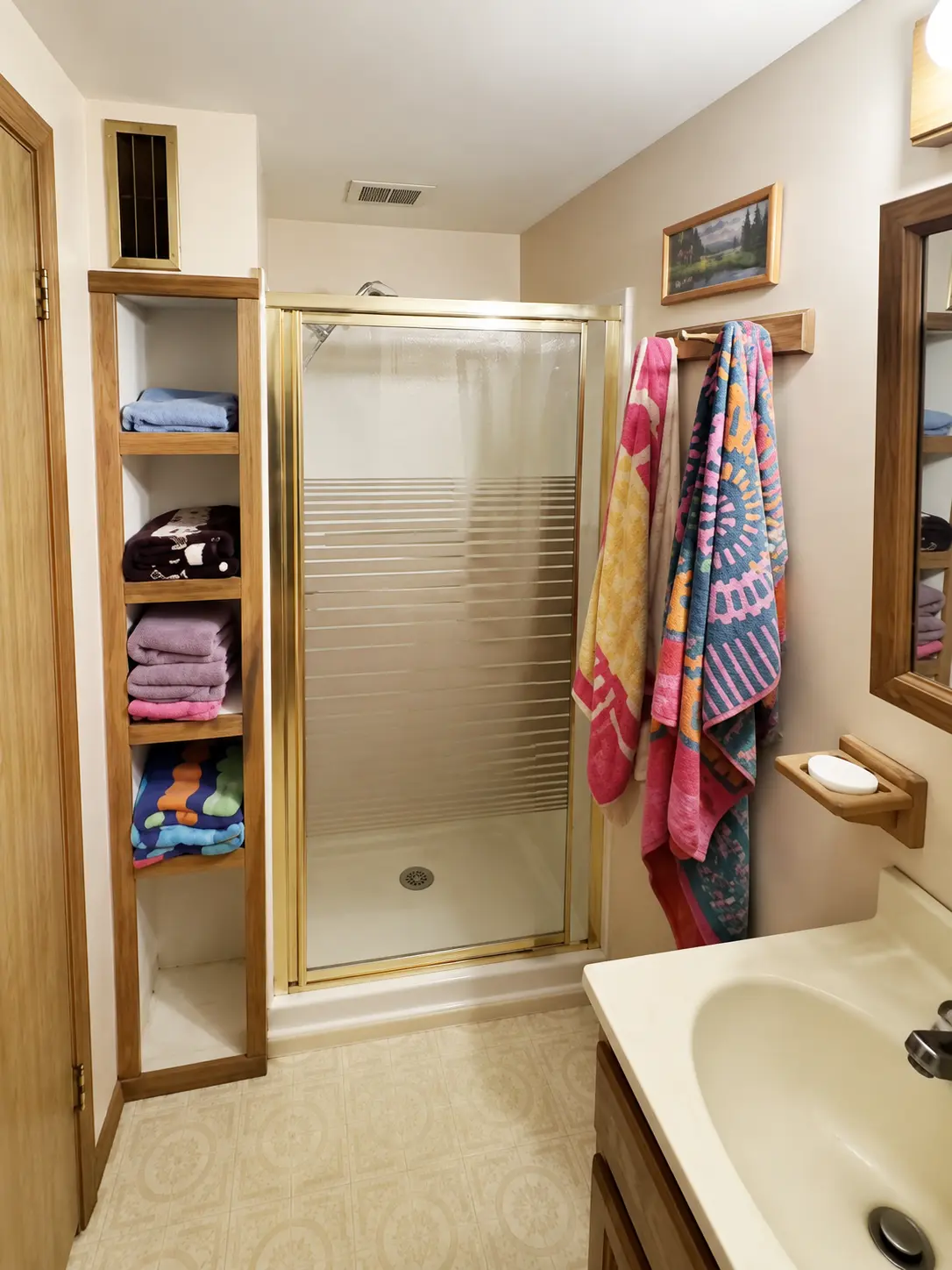 Bathroom with a glass shower enclosure and open shelves stacked with towels