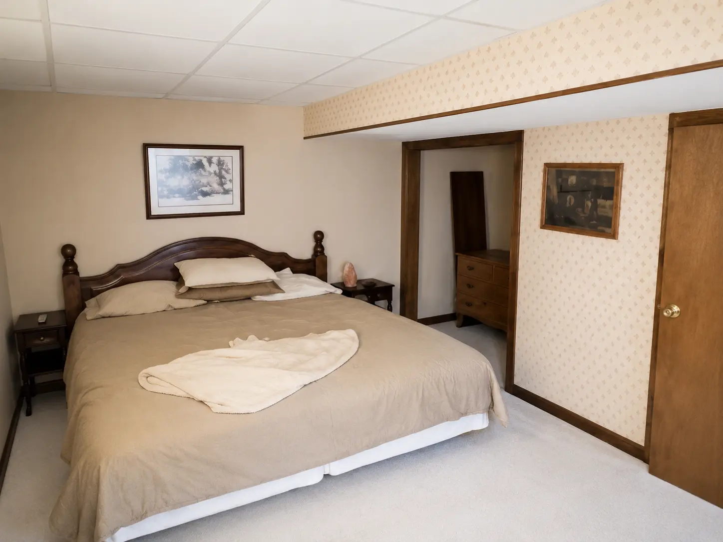 Lower level bedroom with a king bed, carved headboard and two nightstands