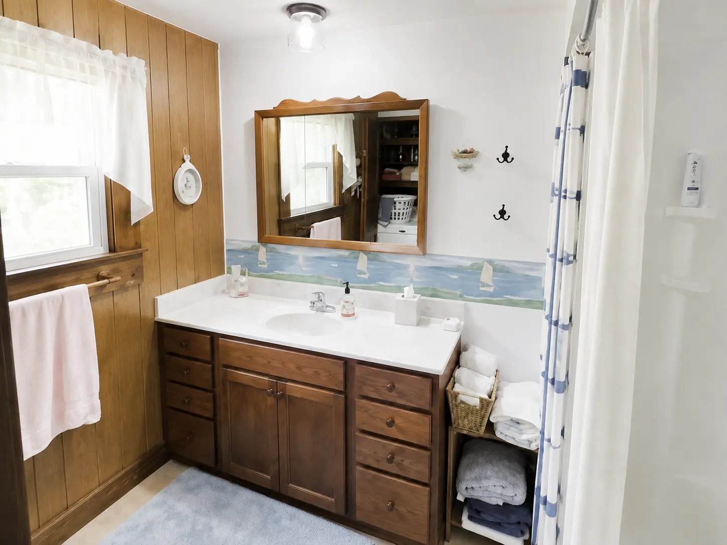 Bathroom with wood paneling, a long vanity and a painted sailboat border