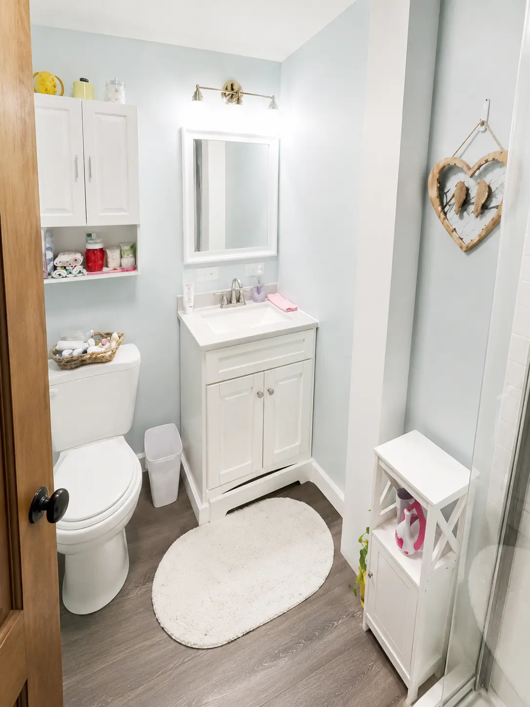 Bright white lower level bathroom with a shower, vanity and wood-look floors